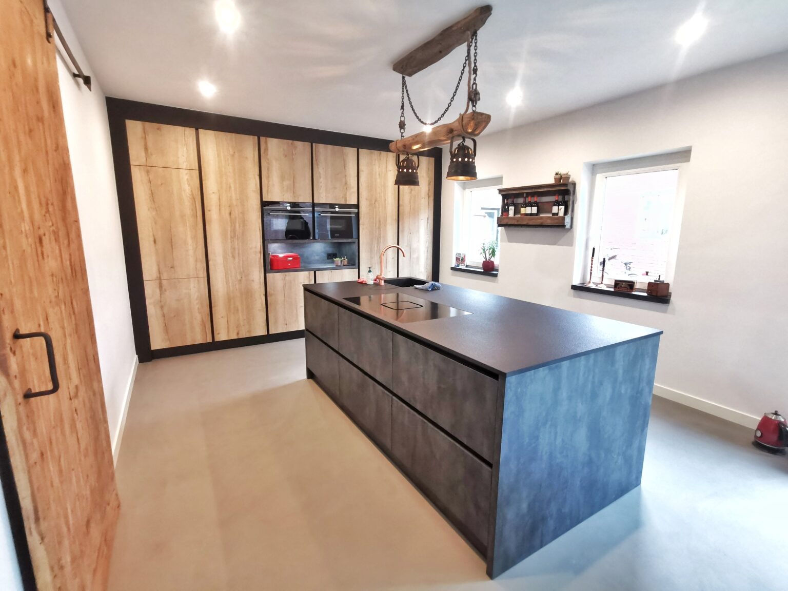 Na: Een stijlvolle mat zwarte industriële keuken met houtlook folie: de keuken na de renovatie
