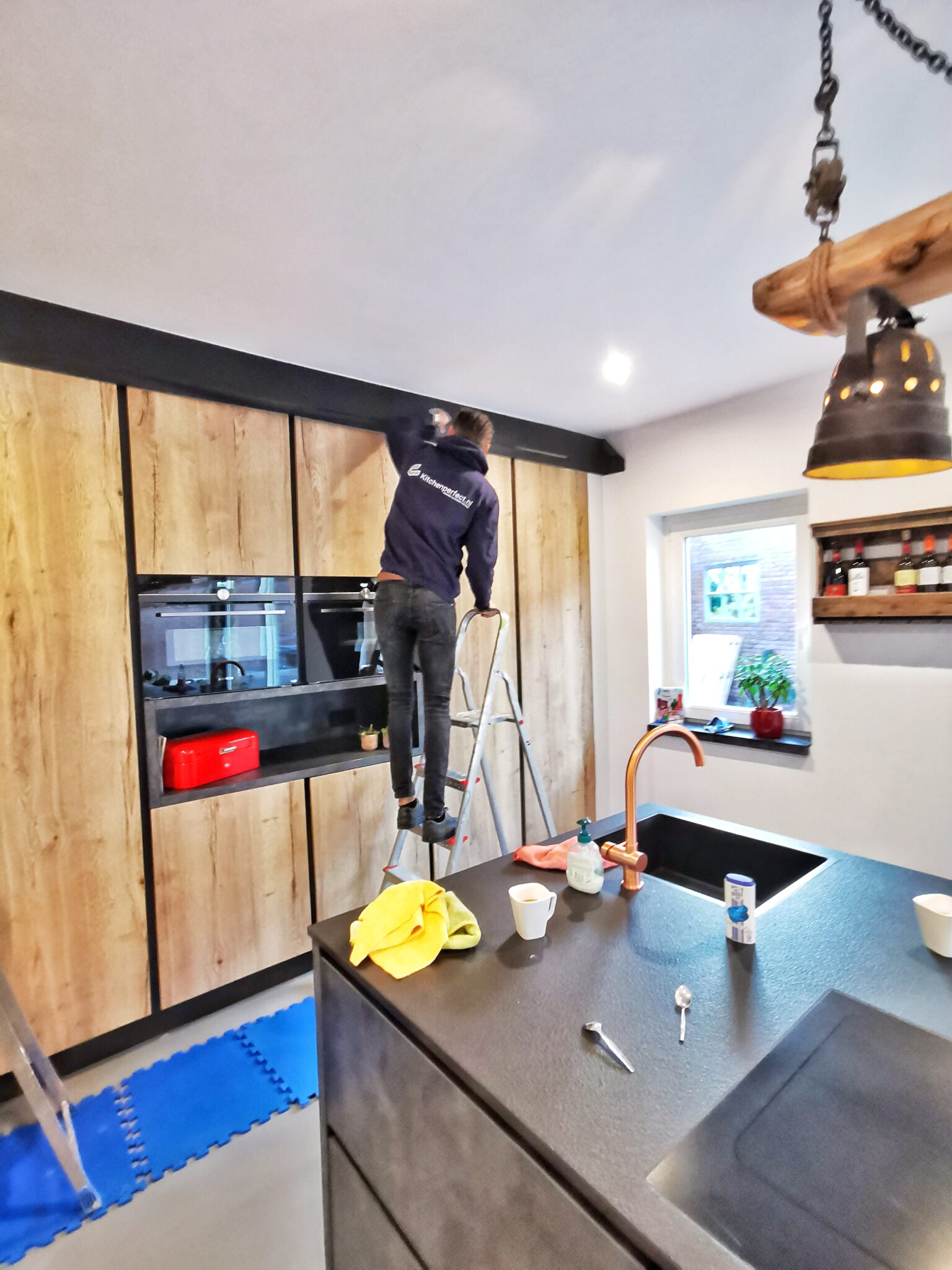 Een stijlvolle mat zwarte industriële keuken met houtlook folie: tijdens de renovatie