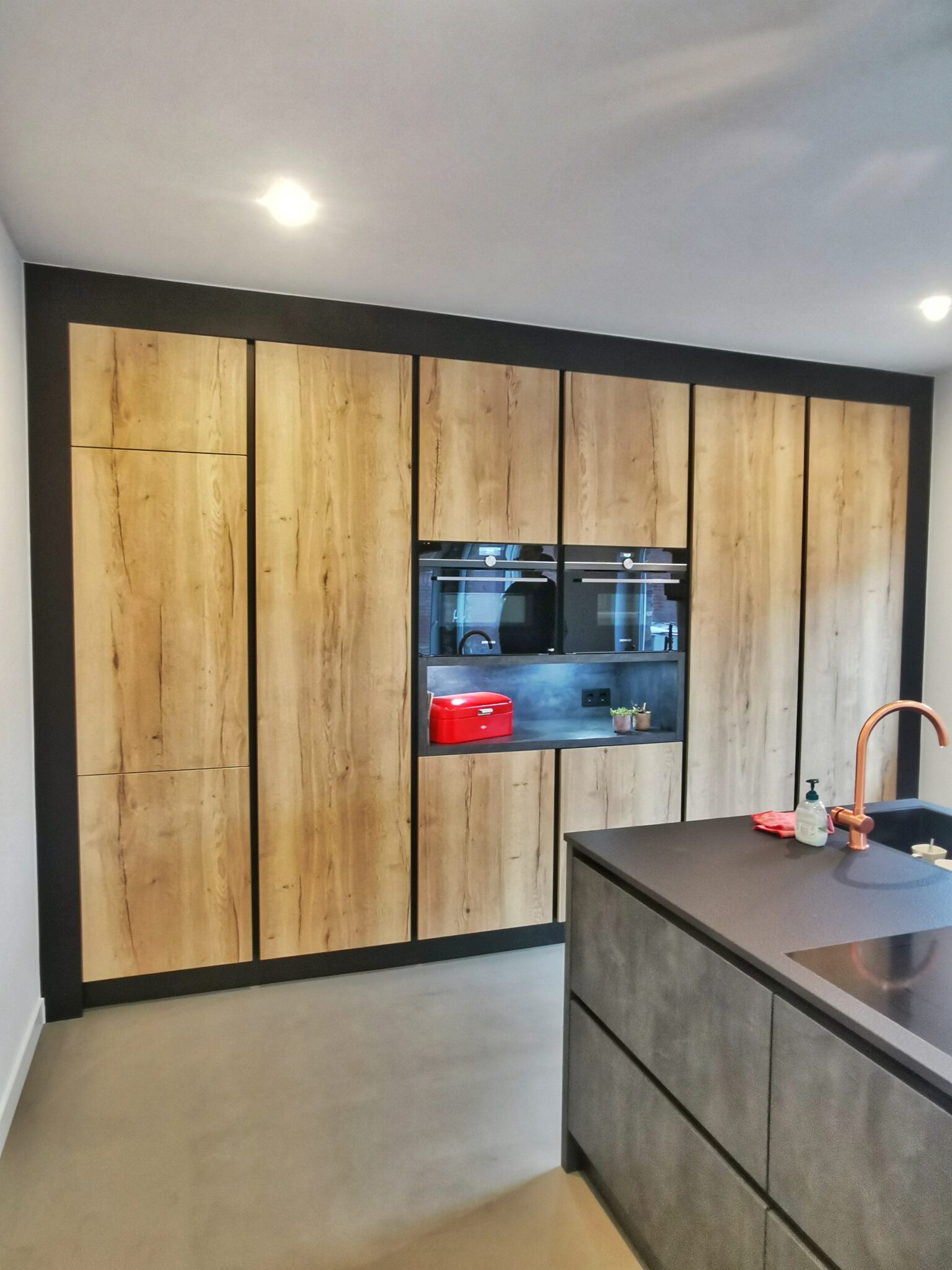 Een stijlvolle mat zwarte industriële keuken met houtlook folie: na de renovatie
