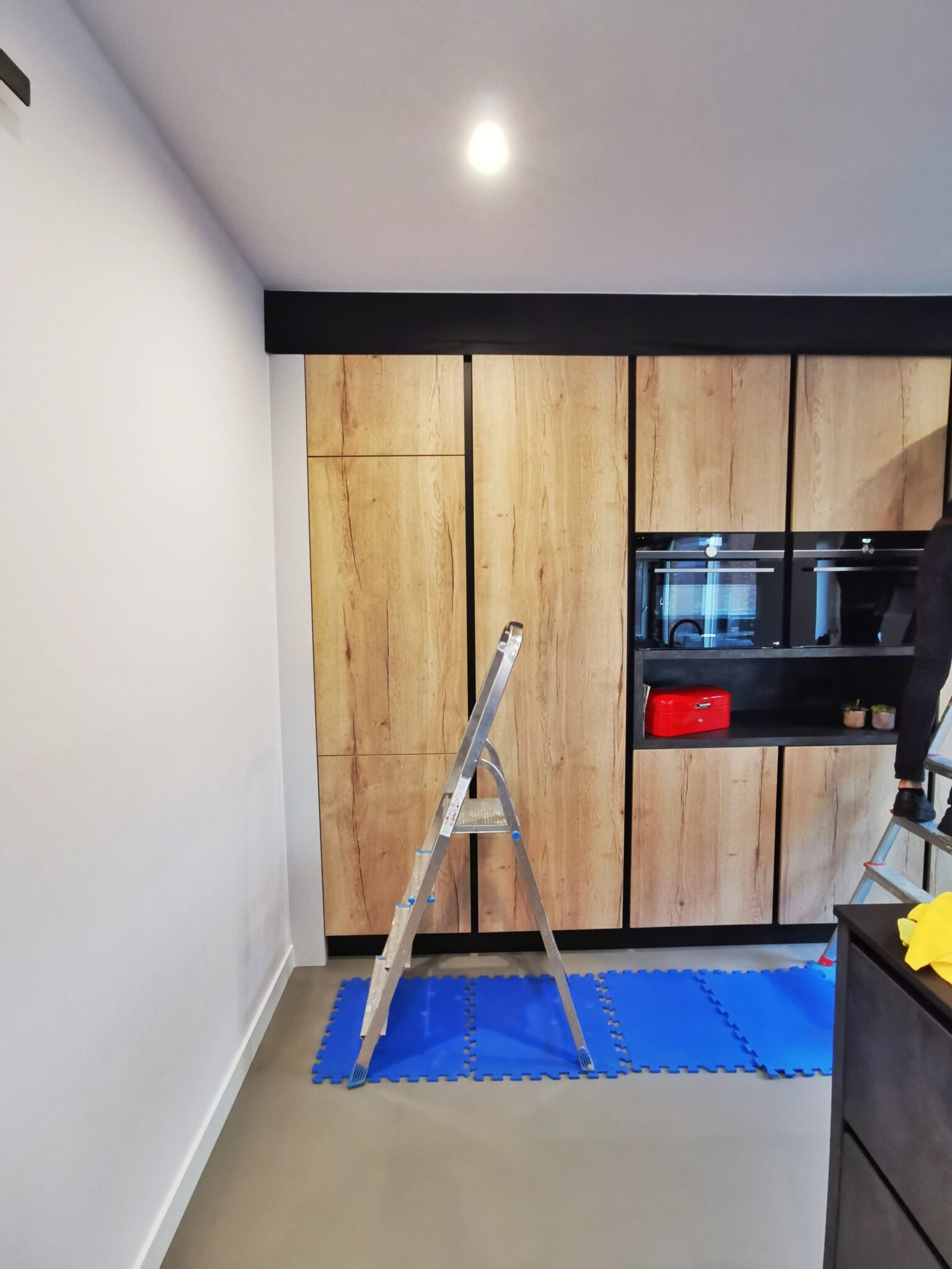 Voor: Een stijlvolle mat zwarte industriële keuken met houtlook folie: de keuken vóór de renovatie